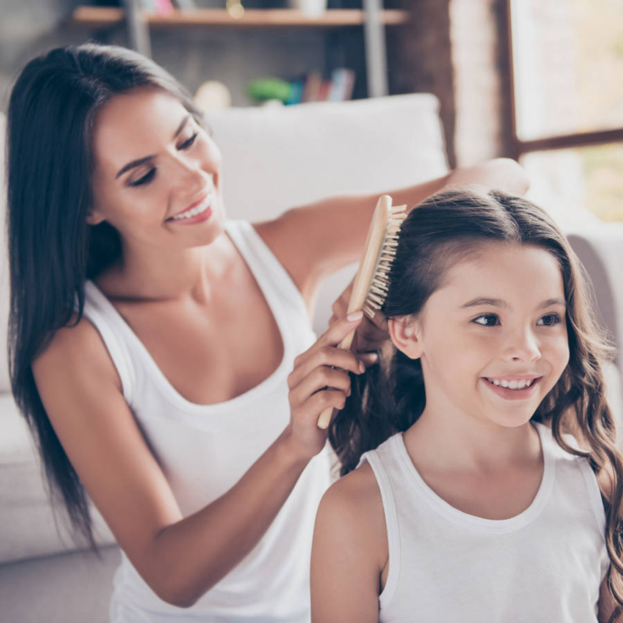 Mujer peinando el cabello largo de una niña